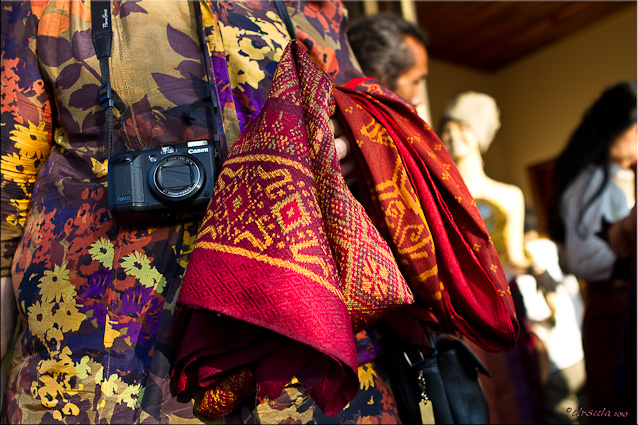 Close-up woman with a camera, with colourful silks over her arm