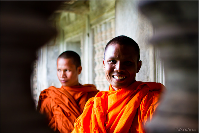 Portrait: Two Theravada monks seen through the balusters of an Angkor Wat corridor