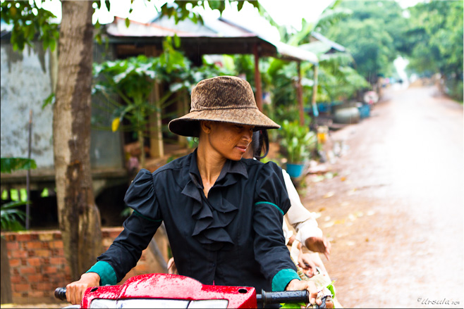 Khmer woman in a brown hat on a red motorcycle