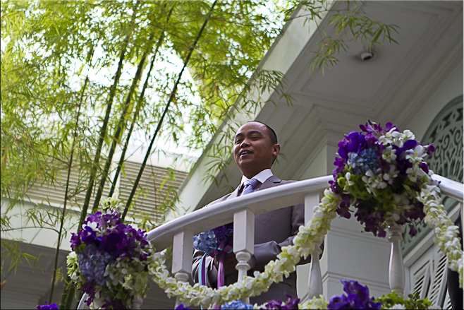 Thai male in a dress suit on a balcony draped in flower arrangements.