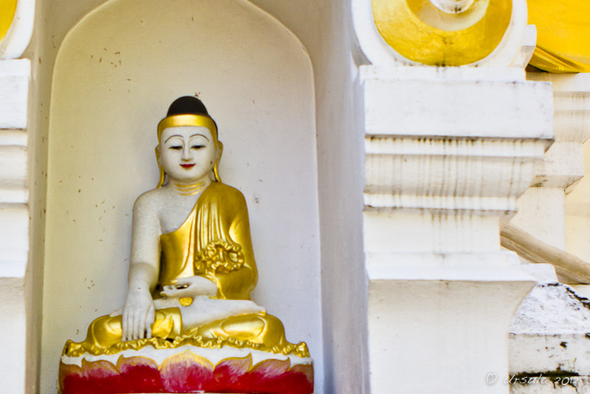 Seated Burmese-style white-stone buddha image in an alcove.