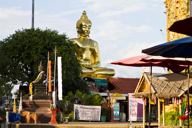 Golden Buddha amid signage, umbrellas, and other images