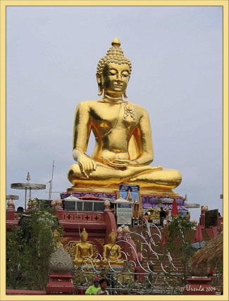 Seated golden Buddha against a gray sky