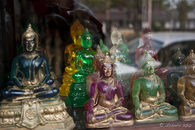 Coloured glass and stone Buddha images in a shop window, Luang Prabang