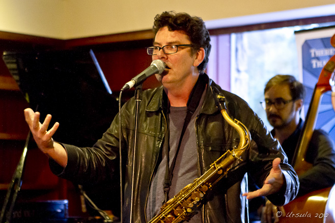 Portrait: man telling a story, saxophone around his neck.