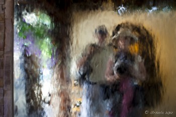 Blurry reflection of man and woman in a water feature.