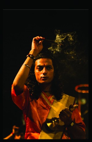 A Hindu male with incense and a gold bell performing and after-dark ganga aarti on the ghats of Varanassi.