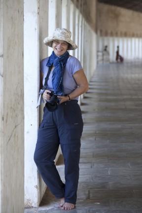 Woman, dressed in blue walk pants and scarf with a camera, in the corridor of a Bagan temple.