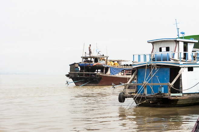Wooden boats under a white-hot sky on the brown Irrawaddy or Ayeyarwady River, Myanmar