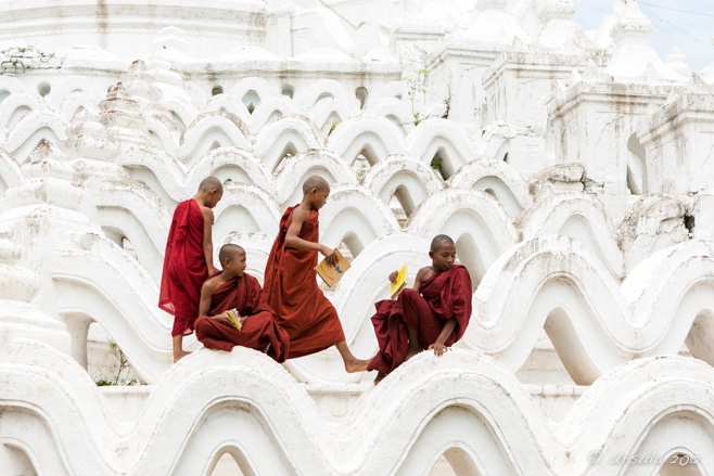 Four young burmese novice monks arrange themselves on the terraces of Hsinbyume Pagoda, Mingun, Myanmar.