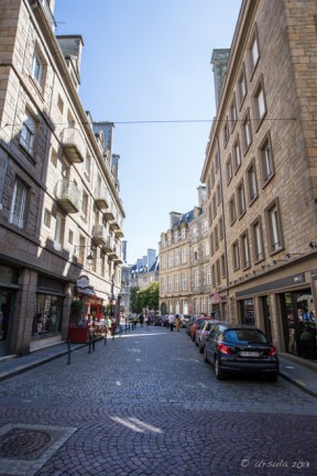 View up a coble-stoned street, modern cars parked along the curb, Rue de Dinan, Saint Malo Brittany France