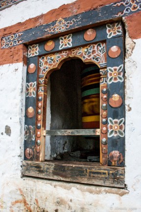 A spinning Bhutanese prayer wheels inside a colourfully painted window, Tiger