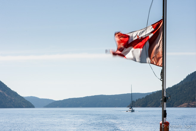 Canadian Flag flapping at the back of a boat, Stuart Channel, BC