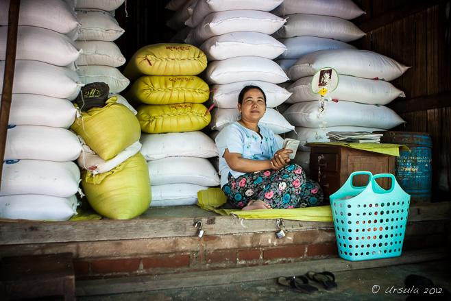 Burmese woman sitting in front of large bags of rice, Market, Bagan Myanmar