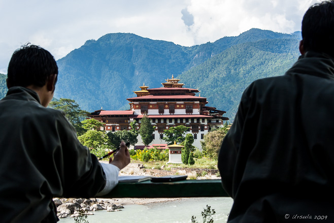 Silhouette of two young Bhutanese men against Punakha Dzong, Bhutan