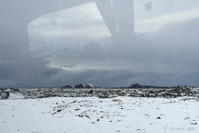 Flat, snowy landscape through a glory bus window, southwest Iceland