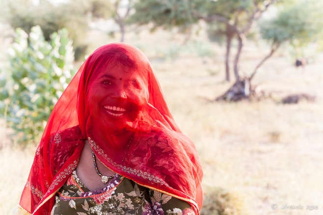 Smiling Indian woman in a red vail, Khiyasariya village, India