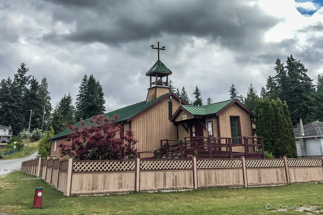 The wooden Our Lady of Lourdes Indian Band Catholic Church in Sechelt under a grey sky, BC Canada