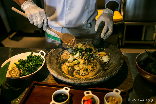 Gloved hands mixing Gado Gado in a stone mortar, Bali Indonesia