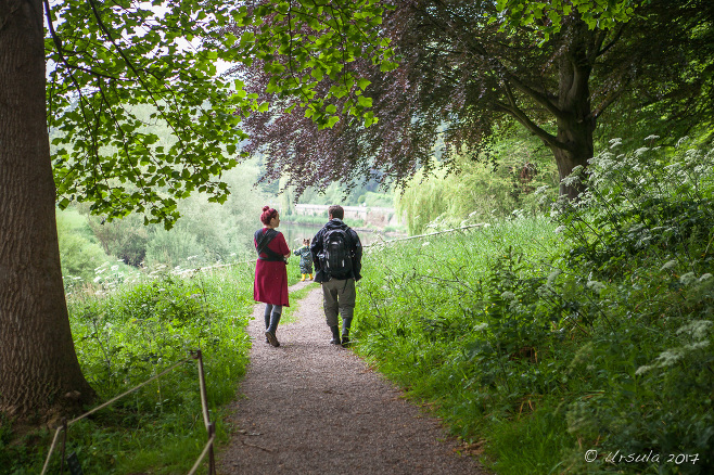 Man and woman with a child on the path, The Weir riverside garden, Herefordshire, UK