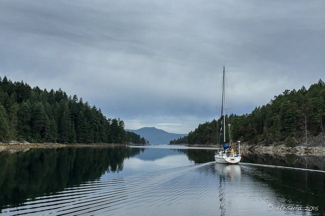 Sailboat motoring out of Ballet Bay, BC