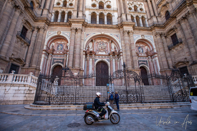 Scooter driving past the front of Málaga Cathedral, Spain