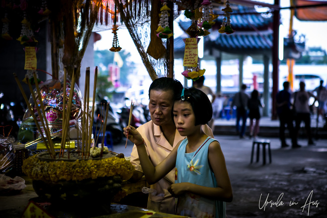 An old woman and a young girl light incense, Chinatown Bangkok