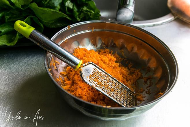 Bowl of grated carrot and a grater.