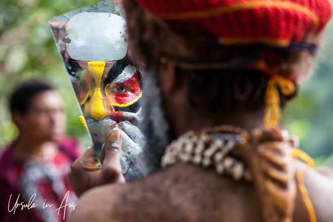 Western Highland man applying face paint in a hand mirror, Paiya Village, Papua New Guinea