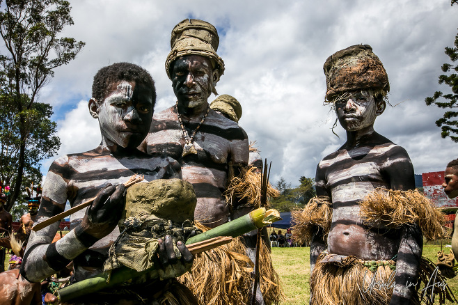 A man and two boys from the Mindima Fire Making Group in sing sing paint, Mt Hagen Papua New Guinea