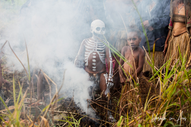 Simbu girl and a skeleton boy in smoke, Mt Hagen, Papua New Guinea.