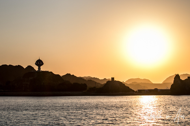 Sunset silhouetting Riyam Incense burner and the Old Watch Tower, Muscat, Oman