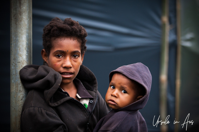 Portrait: Papuan woman and child in front of a plastic-sheeted building, Mt Hagen PNG.