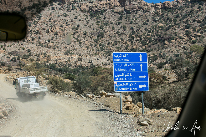 Blue direction sign from inside a car, Hajar Mountains Oman