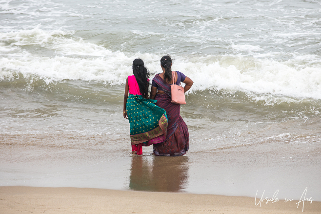 Two women in saris standing in the waves on the Bay of Bengal, Pondicherry India.