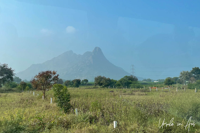 Grassy fields, mountains in the background, from a bus window, Usilampatti India