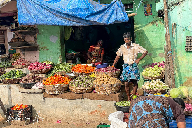 Man outside his house/shop doorway with baskets of vegetables, Usilampatti market, Tamil Nadu Ind